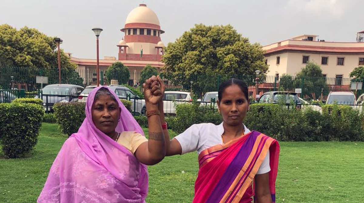 Sokalo Gond of Sonbhadra district and Nivada Rana of Lakhimpur Kheri District stand together outside the Supreme Court of India in Delhi. These two Adivasi women have been an integral part of the legal battle to protect the Forest Rights Act in the Wildlife Trust & Others Vs the Union of India case. Credit: AIUFWP